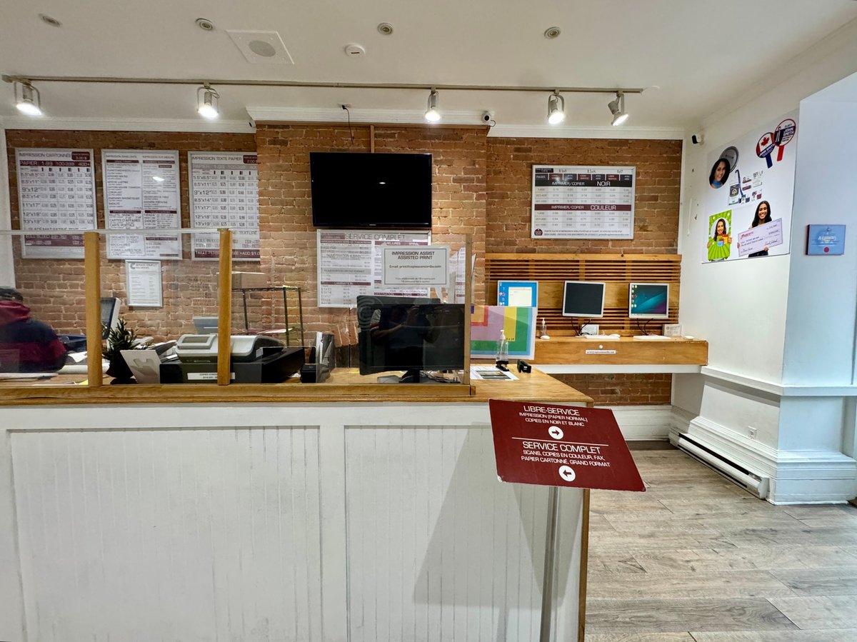 Service counter at Copies Concordia with printed rate sheets and signs on the wall, and a red order-here sign on the counter